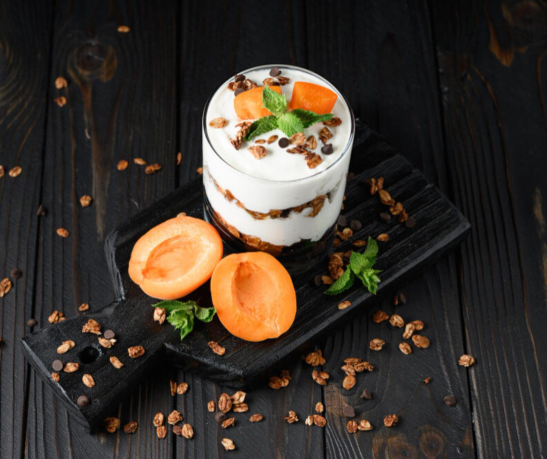 homemade-layered-dessert-with-fresh-apricot-cream-cheese-or-yogurt-granola-on-rustic-background