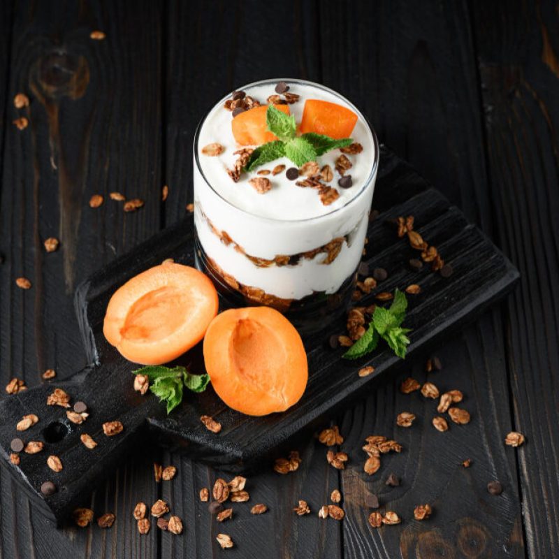 homemade-layered-dessert-with-fresh-apricot-cream-cheese-or-yogurt-granola-on-rustic-background
